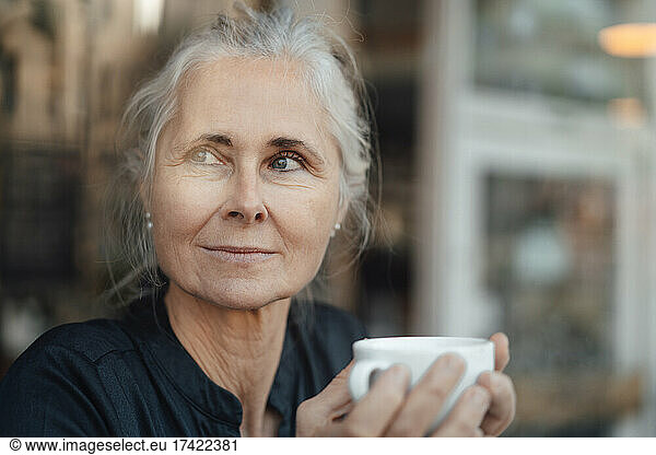 Mature woman holding cup in coffee shop