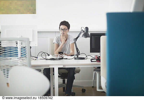 Mature woman holding mobile phone in the office  Freiburg im Breisgau  Baden-Württemberg  Germany