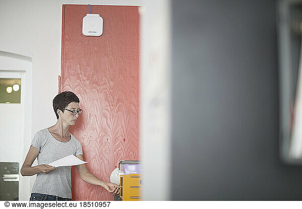 Mature woman holding paper in the office  Freiburg im Breisgau  Baden-Württemberg  Germany