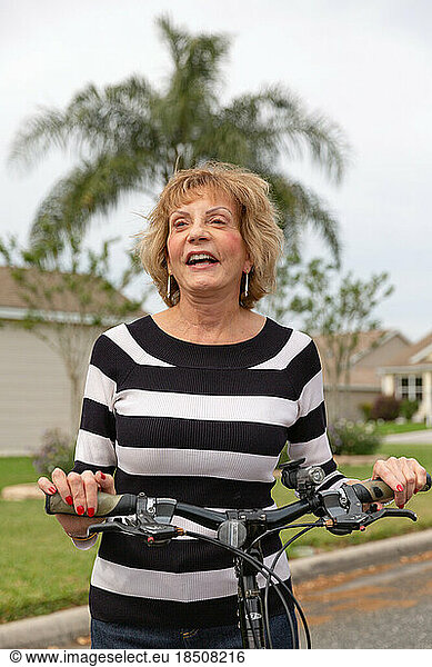 Mature woman in her seventies laughing outside on her bike.