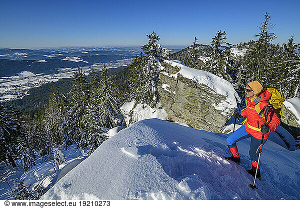 Mature woman in ski-wear hiking on snow covered mountain
