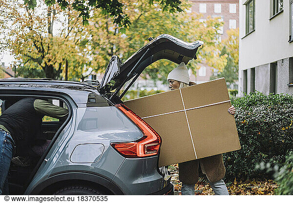 Mature woman loading cardboard in car trunk