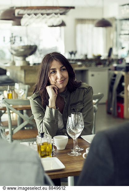 Mature woman looking at colleague during lunch meeting in restaurant