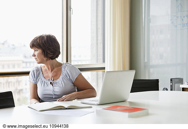 Mature woman looking out from office window
