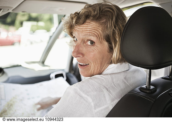 Mature woman looking over shoulder while sitting in car