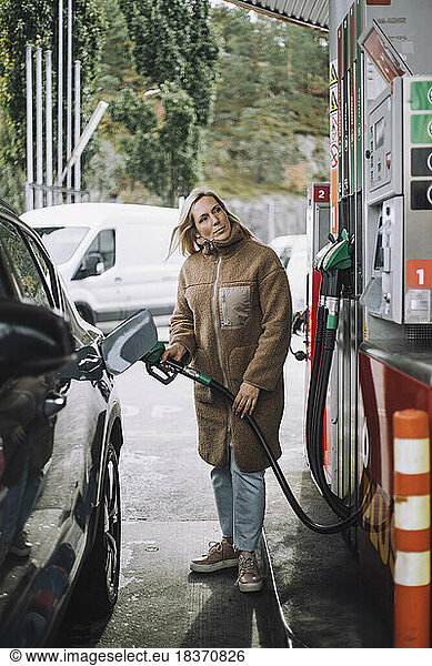 Mature woman refueling car at gas station