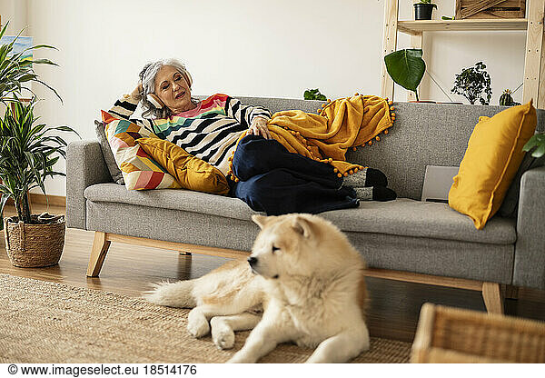 Mature woman relaxing on sofa and listening to music