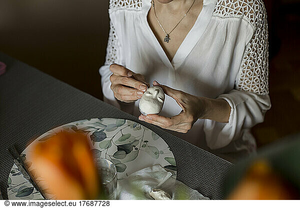 Mature woman sculpting dolls face sitting at home
