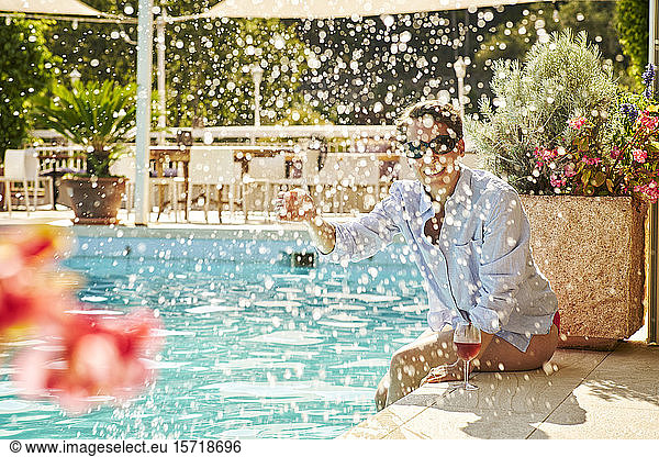 Mature woman sitting at poolside splashing with water