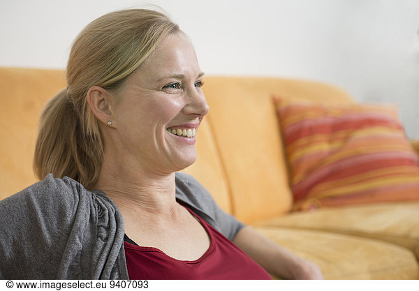 Mature woman sitting on couch  smiling