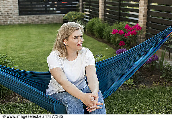 Mature woman sitting on hammock in garden