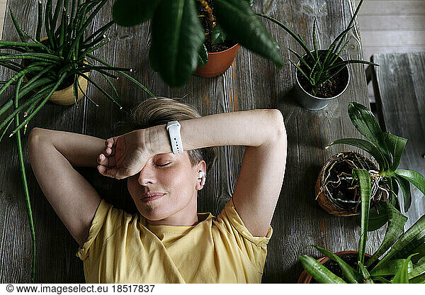 Mature woman sleeping amidst plants at home