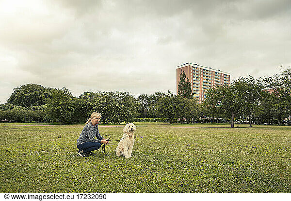 Mature woman spending leisure time with dog in park