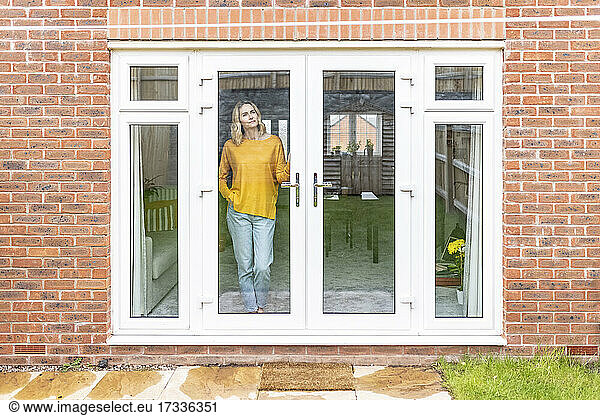 Mature woman standing at door in home