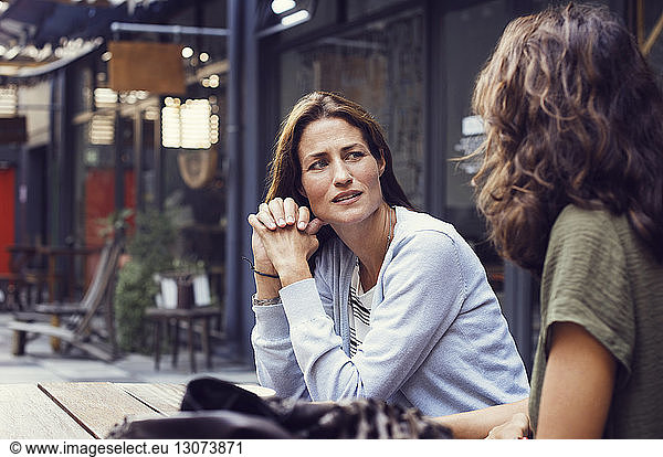 Mature woman talking to friend at sidewalk cafe