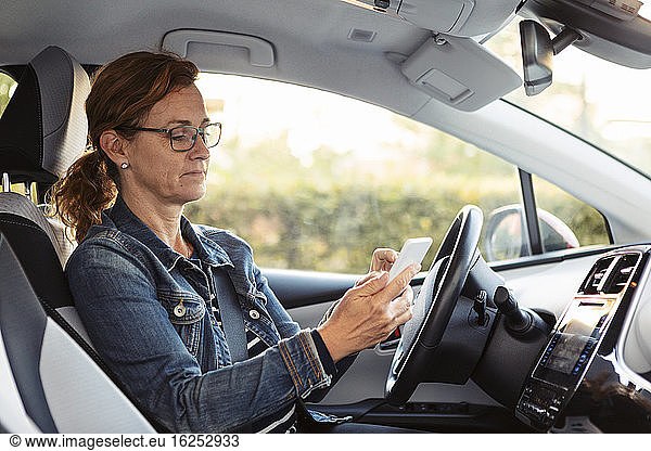 Mature woman texting while sitting in car