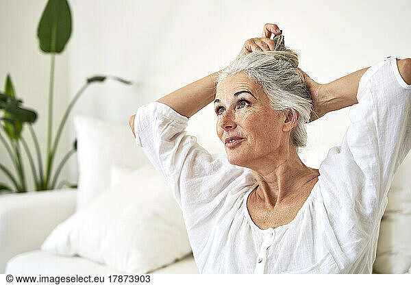 Mature woman tying hair in living room