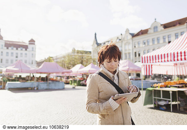 Mature woman using digital tablet at market