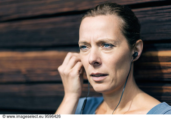 Mature woman using hands-free device outside log cabin