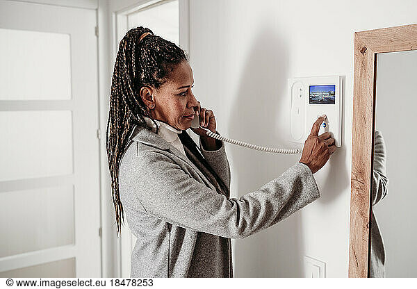 Mature woman using intercom at home