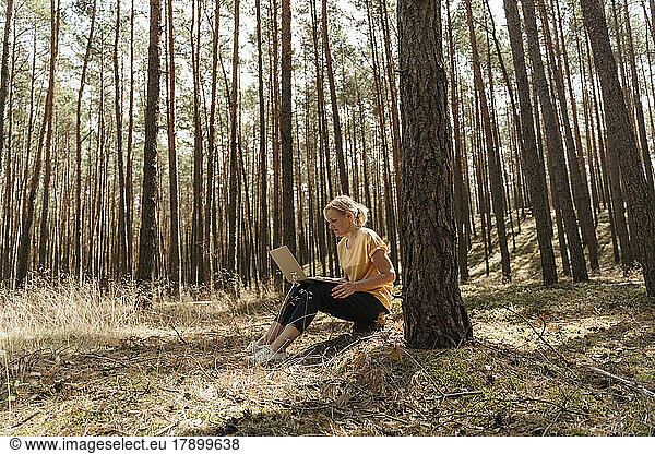 Mature woman using laptop in forest