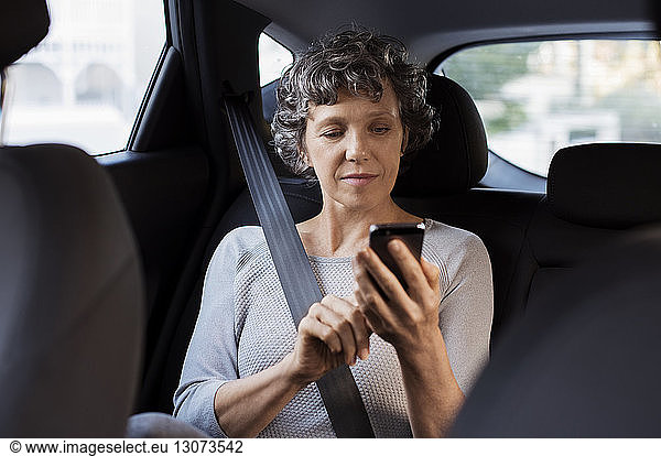 Mature woman using phone while travelling in car