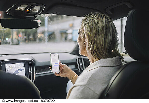 Mature woman using smart phone while sitting in front passenger seat