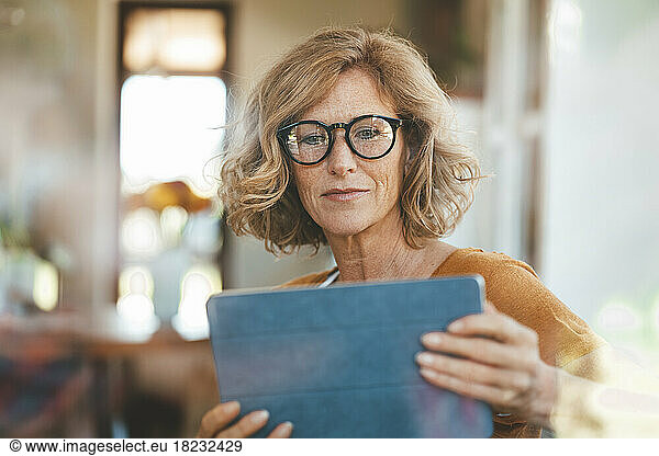 Mature woman using tablet PC sitting at home
