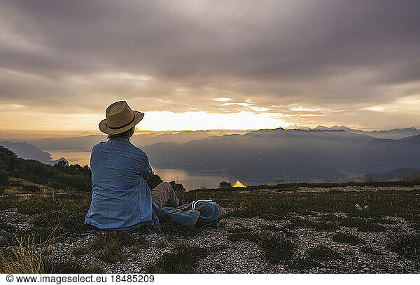 Mature woman wearing hat sitting on mountain