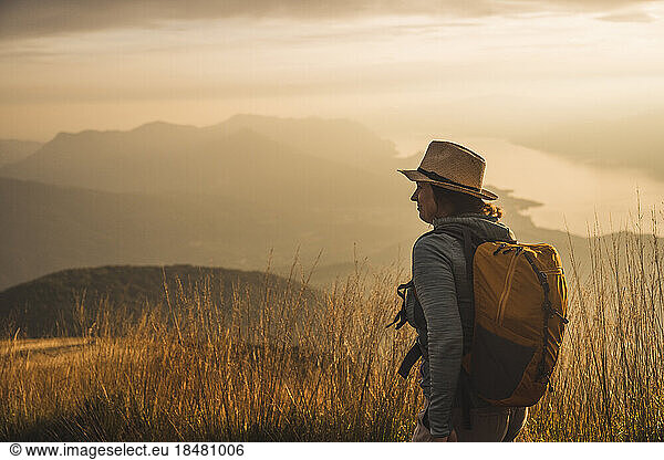 Mature woman wearing hat standing at sunset