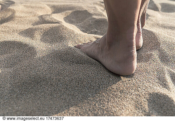 Mature woman with barefoot standing on sand