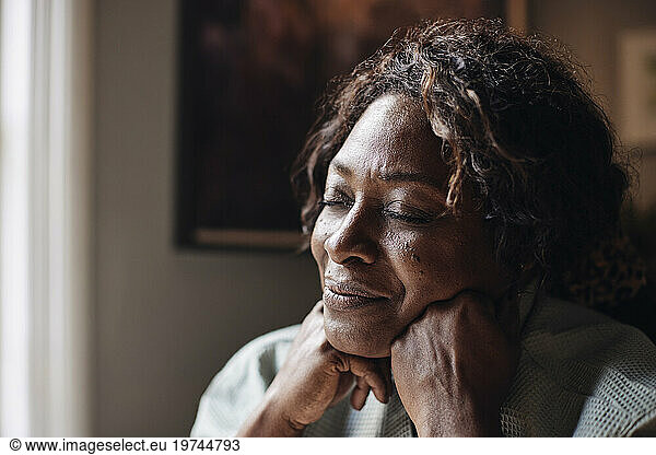 Mature woman with eyes closed day dreaming at home