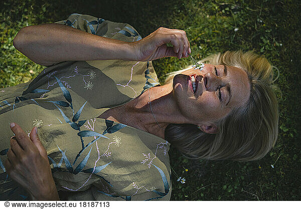 Mature woman with eyes closed smelling flower in garden