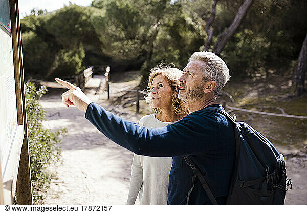Mature woman with man pointing at placard on sunny day