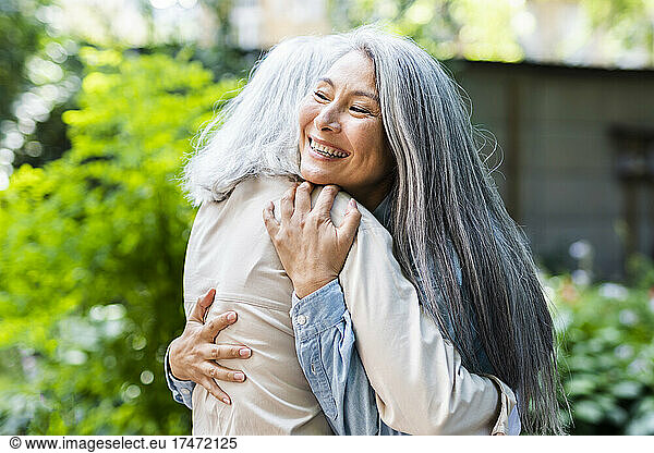 Mature women with long hair hugging female friend