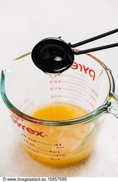 Measuring spoon is used to add oil to a pyrex measuring cup recipe