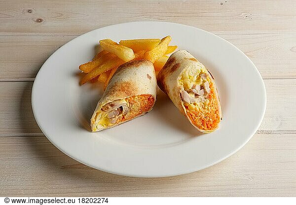Meat  spicy carrot  cabbage and cheese rolled up in thin pitta bread on a plate