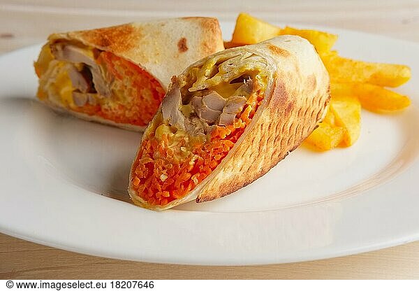 Meat  spicy carrot  cabbage and cheese rolled up in thin pitta bread on a plate