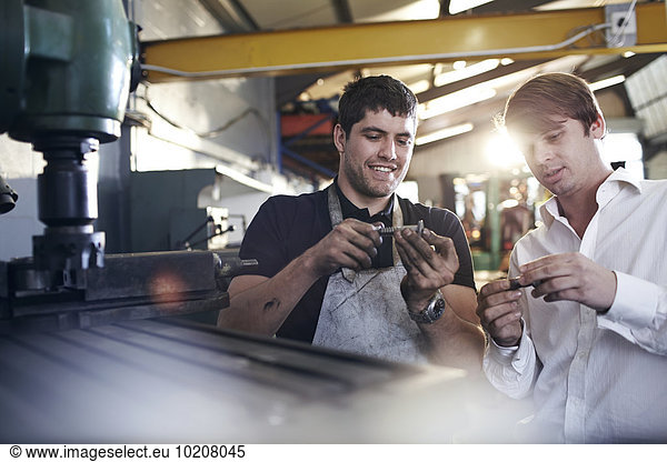 Mechanic and customer examining parts in auto repair shop