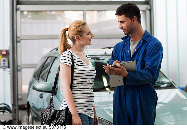 Mechanic discussing car with young woman
