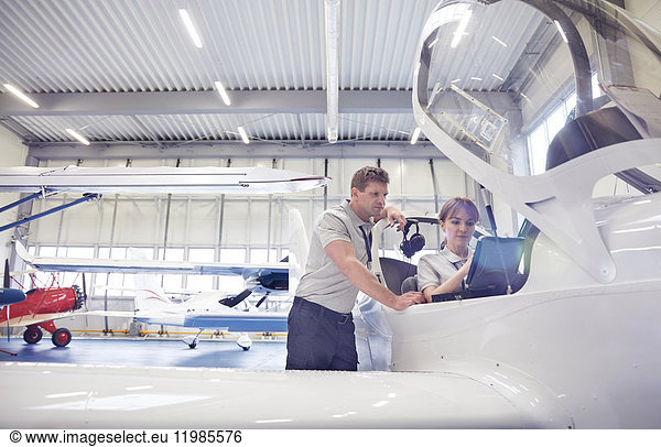 Mechanic engineers working in airplane cockpit in hangar