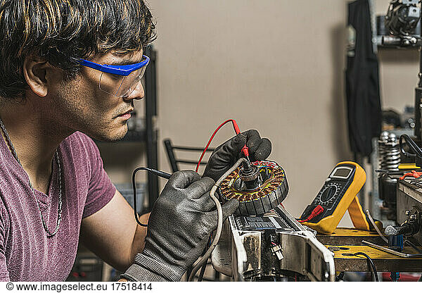 Mechanic using a multimeter to check the voltage of a scooter
