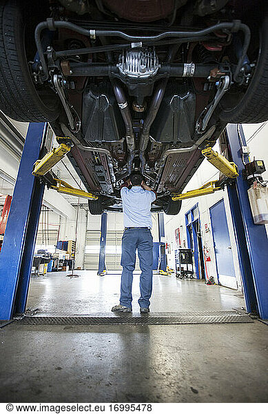 Mechaniker in einer Werkstatt arbeitet an der Unterseite eines Autos auf einer Hebebühne