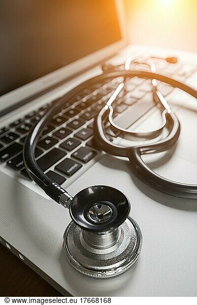Medical stethoscope resting on laptop computer keyboard