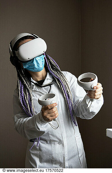 Medical worker in virtual reality helmet is holding joysticks