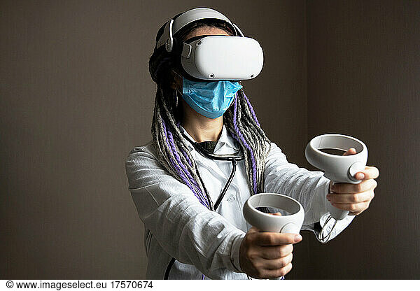 Medical worker in virtual reality helmet is holding joysticks