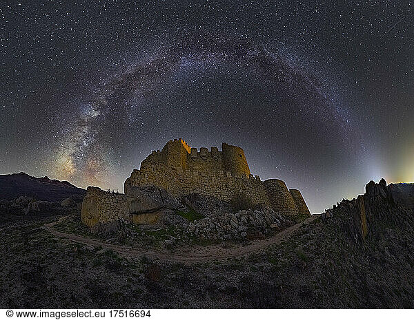 Medieval castle under stars sky with Milky Way arch