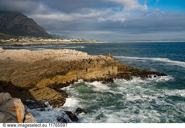 Meereslandschaft mit stürmischer See und Felsen in der untergehenden Sonne am Sievers Point Hermanus Südafrika Afrika