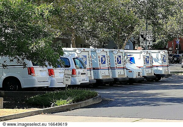 Mehrere Fahrzeuge der United States Postal parken auf dem Parkplatz des örtlichen Postamts.