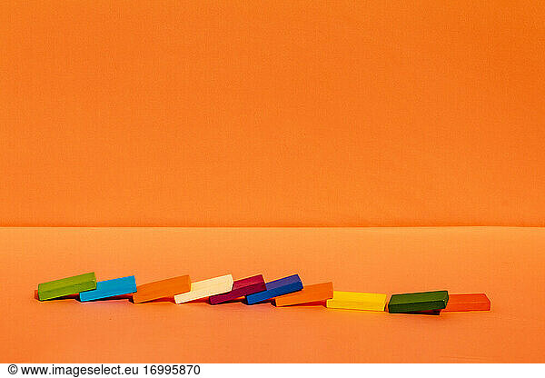 Mehrfarbige Bauklötze fallen auf orangefarbenen Hintergrund